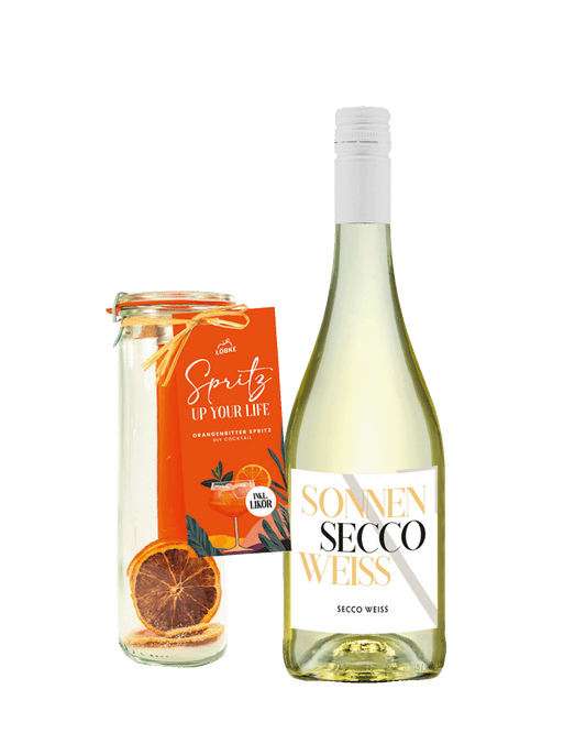 Eine Flasche Secco und dazu ein Weckglas, gefüllt mit getrockneten Orangenscheiben, Zucker und einem Reagenzglas mit Orangenlikör